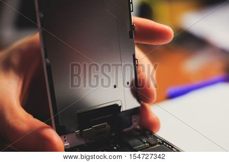 A close-up process of disassemble and dismantle modern mobile phone smartphone with broken shattered display glass and changing details at home