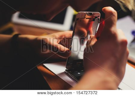 A close-up process of disassemble and dismantle modern mobile phone smartphone with broken shattered display glass and changing details at home