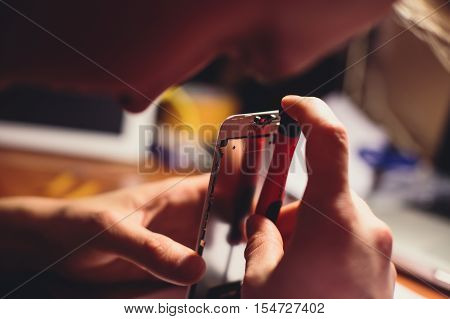 A close-up process of disassemble and dismantle modern mobile phone smartphone with broken shattered display glass and changing details at home