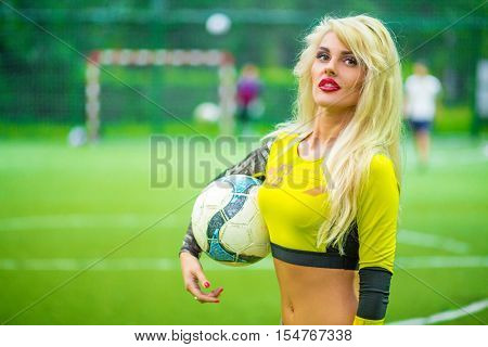 MOSCOW - JUL 16, 2015: beautiful woman (with model release) with ball in hand in yellow top on football field