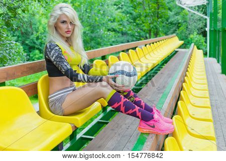 MOSCOW - JUL 16, 2015: Woman (with model release) with ball in her hands in resting on bench near football field