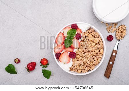 Granola for breakfast with berries yogurt and milk on grey stone background. Healthy eating oatmeal. Concept healhy lifestyle and diet. Top view