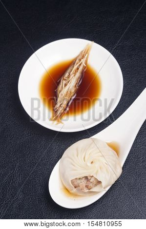 Xiao long bao show it stuff on spoon with dipping sauce