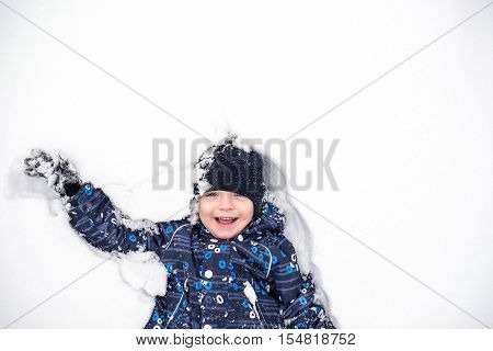 Boy Lies On North Pole Snow. Kis Happy And Smiling.