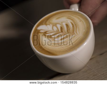 Making latte Art on a Cappucinno on a dark wooden background