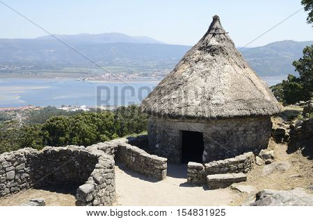 Prehistoric reconstructed house in the remains of a celtic settlement in Santa Tecla Mountain with views to Minho estuary in Galicia Spain.