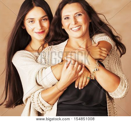 cute pretty teen daughter with mature mother hugging, fashion style brunette makeup close up tan s, real warm colors
