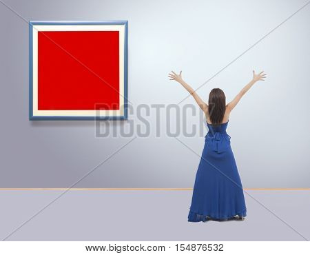 Woman standing inside a gallery in front of picture frames with hands up. Film grain is added for better impression NOTE:This image is composite of more photos.