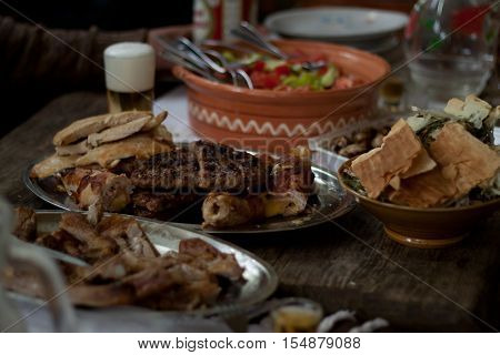 Traditional Macedonian food different kind of meat, salats, breads, beer and Rakia - krvavica sausage with shopska salad, shallow dof