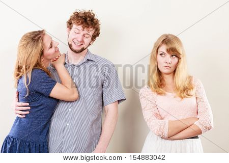 Jealousy and betrayal concept. Abandoned jelous girl watching on happy hugging couple. Triangle relationship.