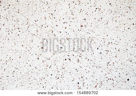 Orange yellow red blue colorful stones and pebbles on a white wall background closeup