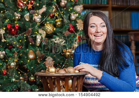 lady in blue sweater watches to somewhere and laughs in the living room, she tuches new year's golden balls