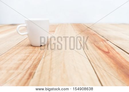 White cup on wooden table and cement wall backgroundSoft focus
