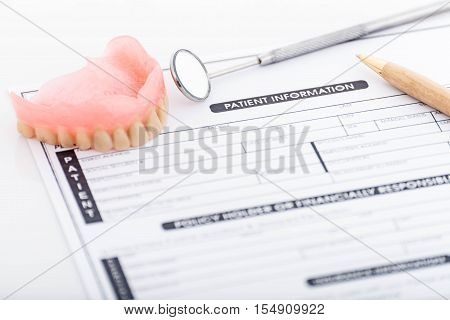 Patient information form and dentures with dental glass with pen on white background
