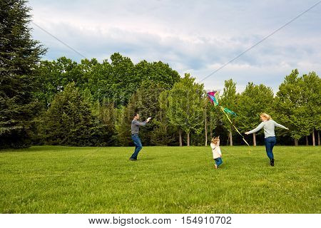 Happy Young Family With Flying A Kite.