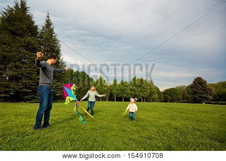 Happy Young Family With Flying A Kite.