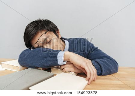 Asian man asleep on the table. gray background