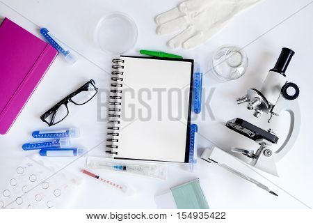 doctor workplace with microscope and blank open notebook at lab top view