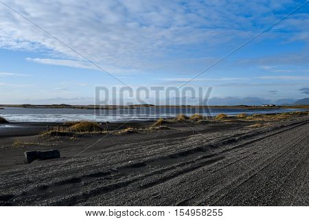 black volcanic lava stone road with beautiful landscape in summer season near Stokksness Iceland