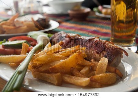 Traditional Macedonian food different kind of meat, salats, breads, beer and Rakia - krvavica sausage with shopska salad, shallow dof