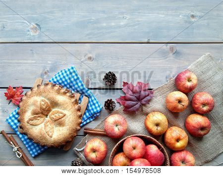 Apple pie with fruit ingredients and cinammon sticks on a wooden table