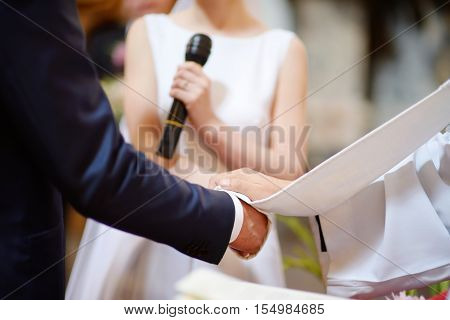 Bride And Groom's Hands Wrapped In Priest's Cassock