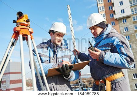 Surveyor workers with level at construction site