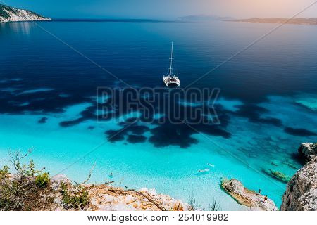 White Catamaran Yacht At Anchor In Calm Clear Azure Water Lagoon. Unrecognizable Tourists Relax And 