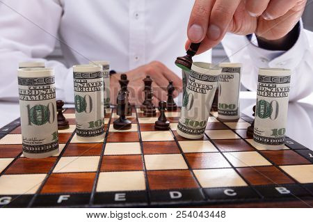 Close-up Of A Person Falling Rolled Up Banknote With Chess Piece