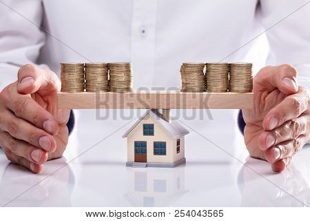 Businessman Protecting Stacked Coins On Seesaw