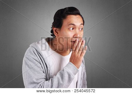 Young Asian Man Wearing Jacket Whispering And Gossiping
