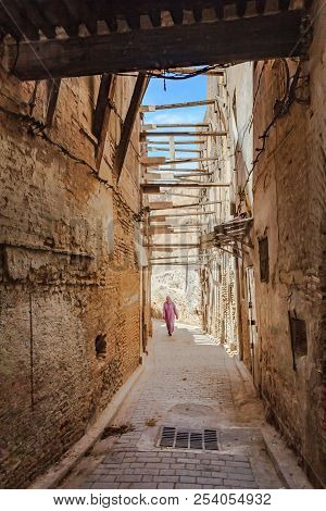 Unidentifyable Woman In Kaftan, Berber Clothing Walking On A Narrow Street In Fes Medina In Morocco