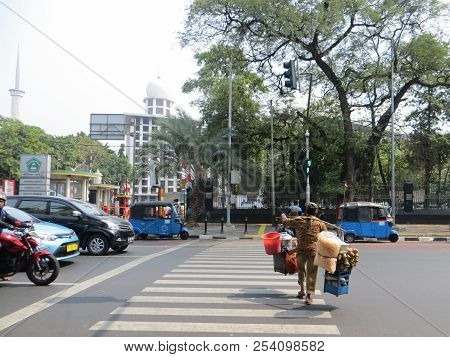 Jakarta, Indonesia - August 2, 2018: A Street Food Vendor Crossing The Road Through A Pelican Crossi