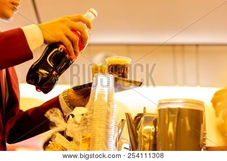 Shot In Low Light Flight Attandant Serving A Drink To Passengers On Seats During Flight Time.