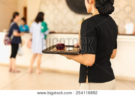 Waitress With Welcome Drink On A Tray At Hotle Reception.