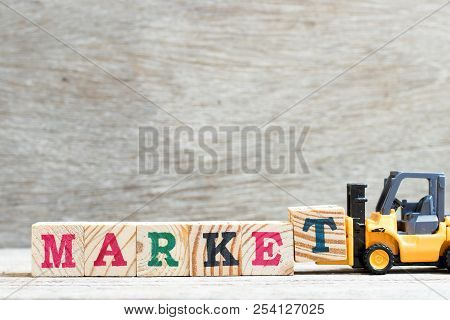 Toy Forklift Hold Letter Block T To Complete Word Marekt On Wood Background