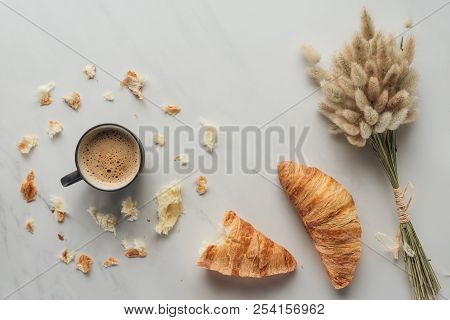 Top View Of Cup Of Coffee With Croissants And Bouquet Of Bunnytail Ears On White Marble