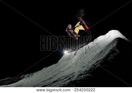 Freeride Snowboarder With Dreadlocks Dressed In The Warm Sportswear Is Jumping In Powder Snow At Nig