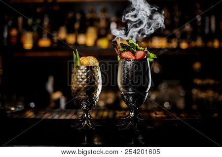 Two Glasses Of Fresh Summer Cocktails Decorated With Fruit And Fume On The Bar Counter