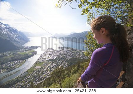Girl Hiker With A Backpack And Trekking Pole Sitting And Looking On Romsdalsfjorden And Andalsnes, N