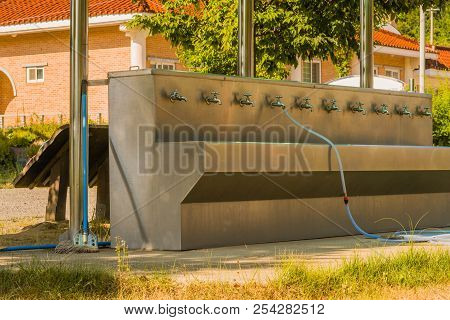 Multifaceted Public Washing Sink And Water Fountain With Hose Attached To Faucet At Edge Of Public P