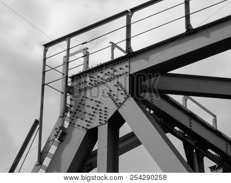 Fragment Of Metal Train Track Bridge In The Industrial Area. Bottom View. Urban Grunge. Black And Wh