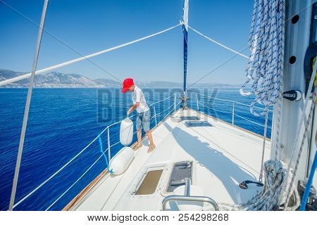 Cute Boy On Board Of Sailing Yacht On Summer Cruise. Travel Adventure, Yachting With Child On Family