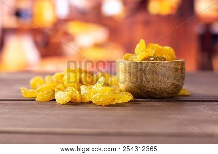 Lot Of Whole Dry Golden Raisins Sultana Variety With Wooden Bowl With Rustic Wood Kitchen In Backgro
