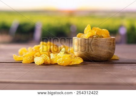 Lot Of Whole Dry Golden Raisins Sultana Variety With Wooden Bowl With Vineyard In Background