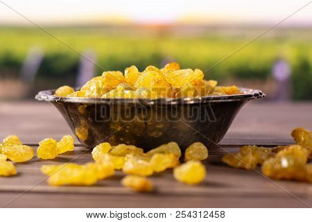 Lot Of Whole Dry Golden Raisins Sultana Variety In Old Iron Bowl With Vineyard In Background