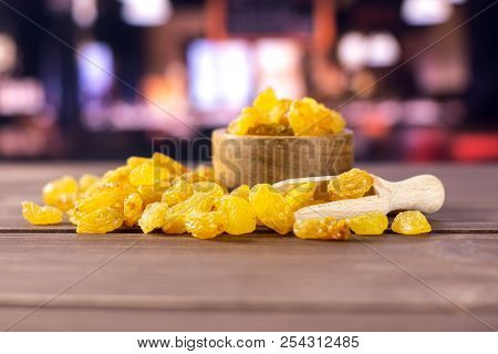 Lot Of Whole Dry Golden Raisins Sultana Variety Scoop With Wooden Bowl With Restaurant In Background