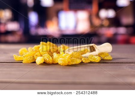 Lot Of Whole Dry Golden Raisins Sultana Variety With Wooden Scoop With Restaurant In Background