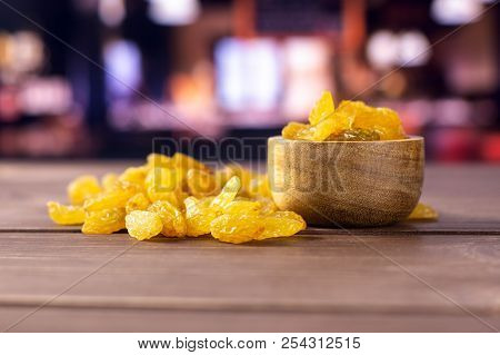 Lot Of Whole Dry Golden Raisins Sultana Variety With Wooden Bowl With Restaurant In Background