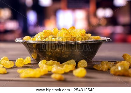 Lot Of Whole Dry Golden Raisins Sultana Variety In Old Iron Bowl With Restaurant In Background